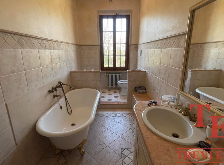 Spacious bathroom with tub, window, and dual sinks.