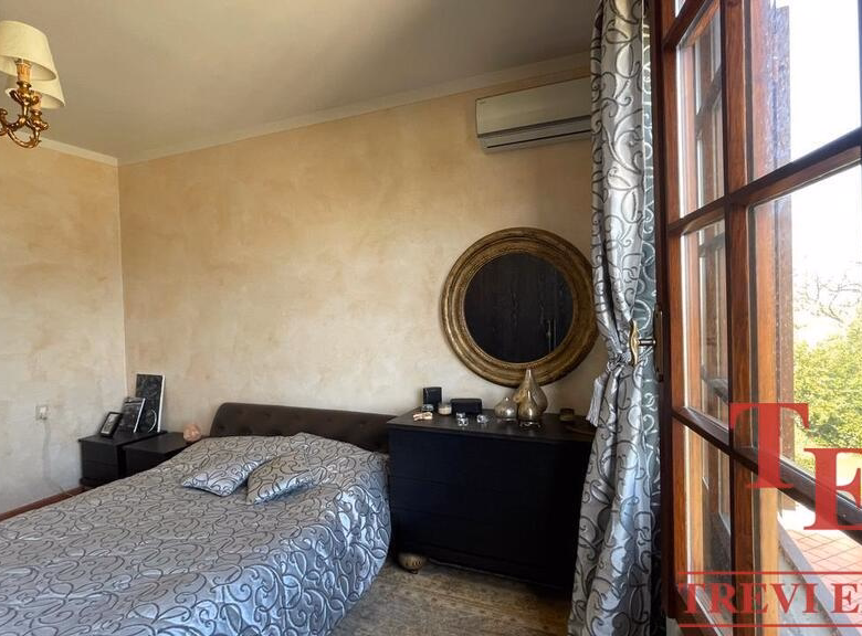 Elegant bedroom with large window and vintage chandelier.