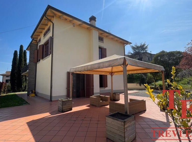 Sunny garden with gazebo at spacious two-story house.