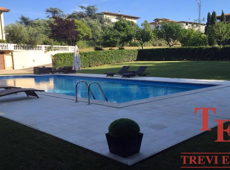 Luxurious backyard with pool and lounge chairs.