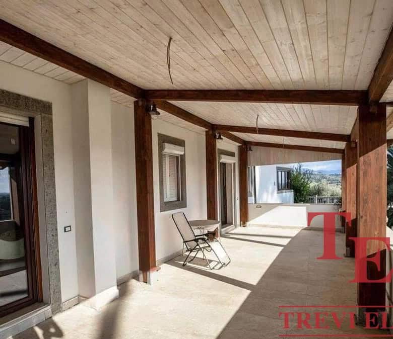 Spacious Italian balcony with wooden beams, overlooking lush greenery and a scenic landscape, ideal for enjoying outdoor living.