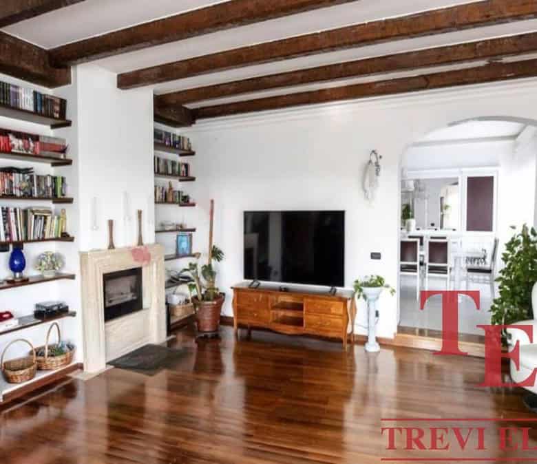 Sophisticated living room with wooden ceiling beams, built-in bookshelves, a fireplace, and a large flat-screen TV for a luxurious Italian home.