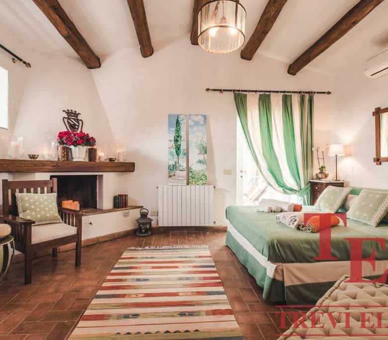 Luxurious Italian bedroom featuring rustic wooden ceiling beams, elegant green and white colour scheme, and charming decor perfect for a serene property in Italy.