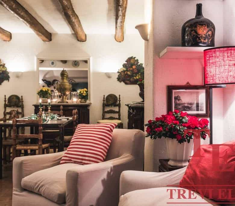 Charming Italian living room with exposed wooden beams, cosy armchairs, and vintage decor in a traditional style. Elegant furniture and warm lighting create a welcoming atmosphere.
