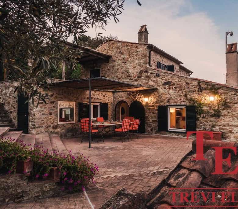 Rustic Italian stone cottage with outdoor dining area, surrounded by lush plants and scenic countryside, perfect for luxurious real estate in Italy.