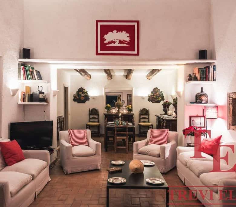Cozy Italian living room with white sofas, red cushions, and decorative indoor plants, featuring warm lighting and rustic wooden accents for an inviting atmosphere.