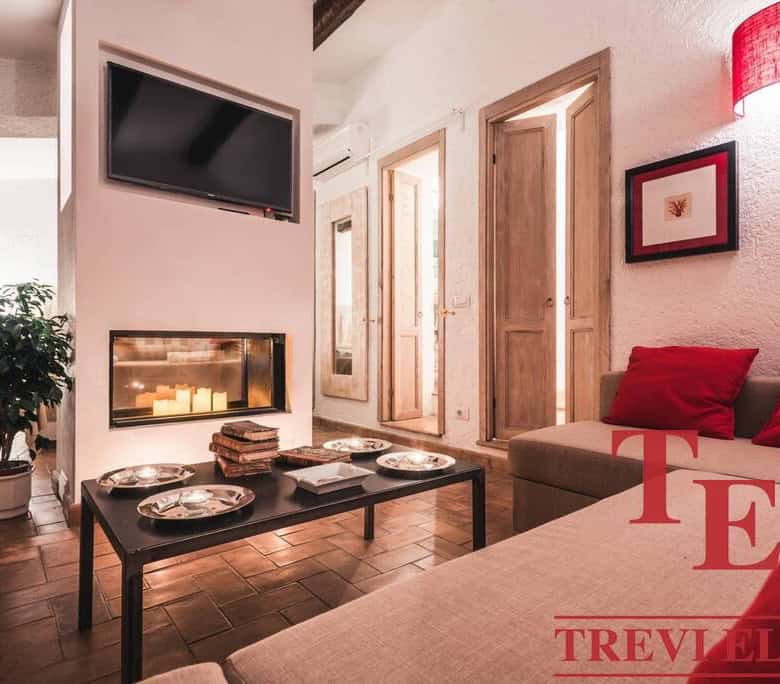 Cozy living room with modern decor, warm lighting, and a fireplace, located in a luxurious Italian property listed by Trevi Elite.
