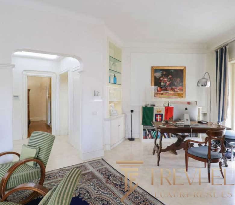 Luxurious Italian living room featuring elegant furniture, artwork, and large windows with balcony access, showcasing premium Italian real estate by Trevi Elite.