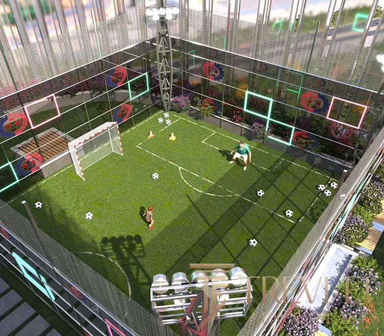 Modern rooftop football pitch with artificial grass, goalposts, and scattered soccer balls, surrounded by glass walls decorated with colourful neon lights and floral designs.