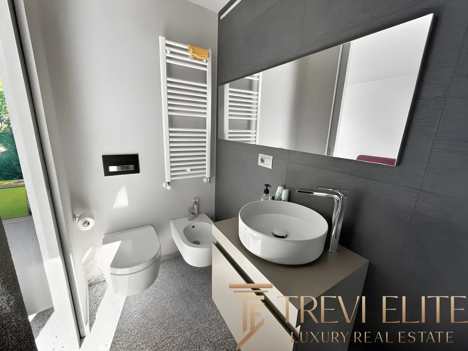Modern bathroom with a round vessel sink, grey tiling, and minimalist mirror.
