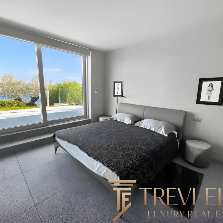 Master bedroom with a large window and minimalist black-framed accents.