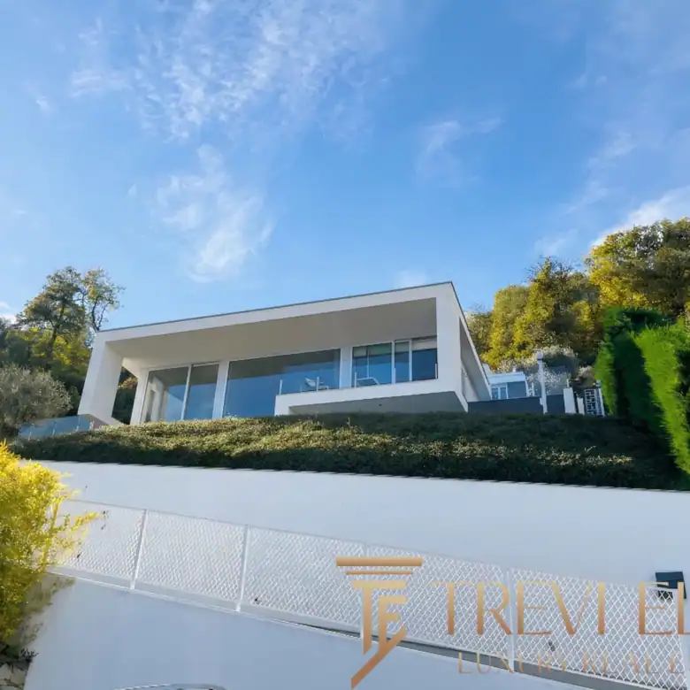 Modern white exterior with steps leading to a glass-railed balcony.