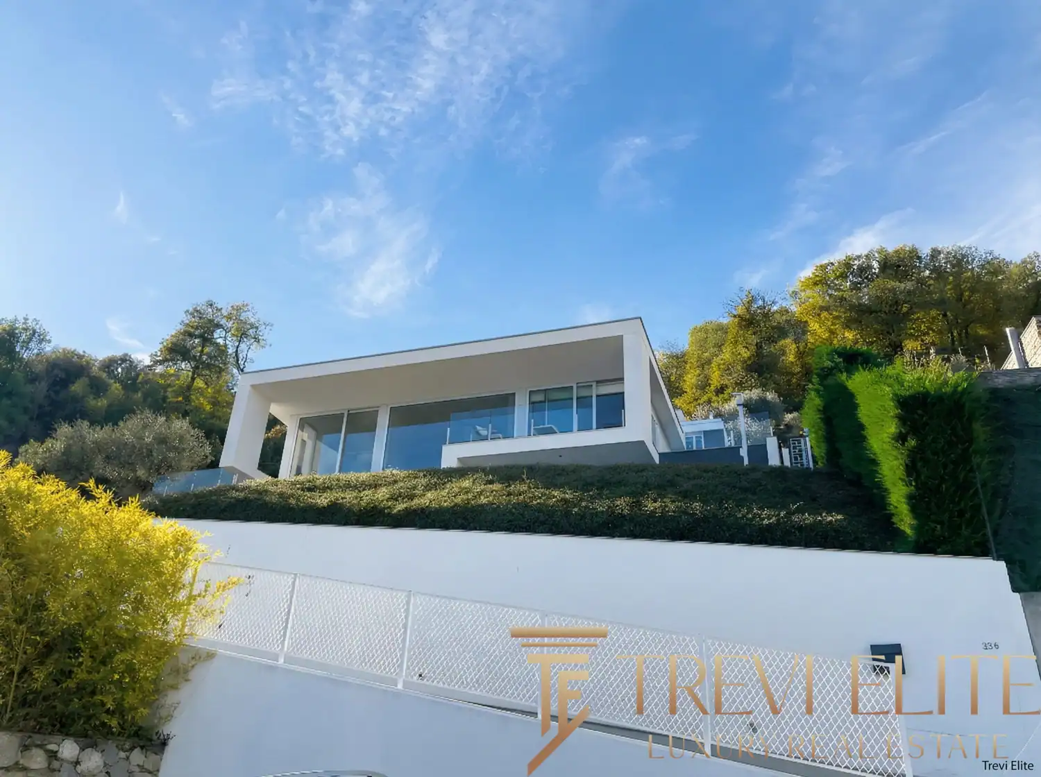 Modern white exterior with steps leading to a glass-railed balcony.