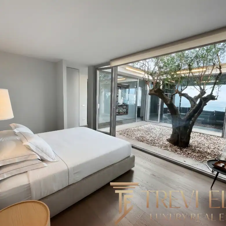 Cozy bedroom with warm lighting and a view of the courtyard tree.