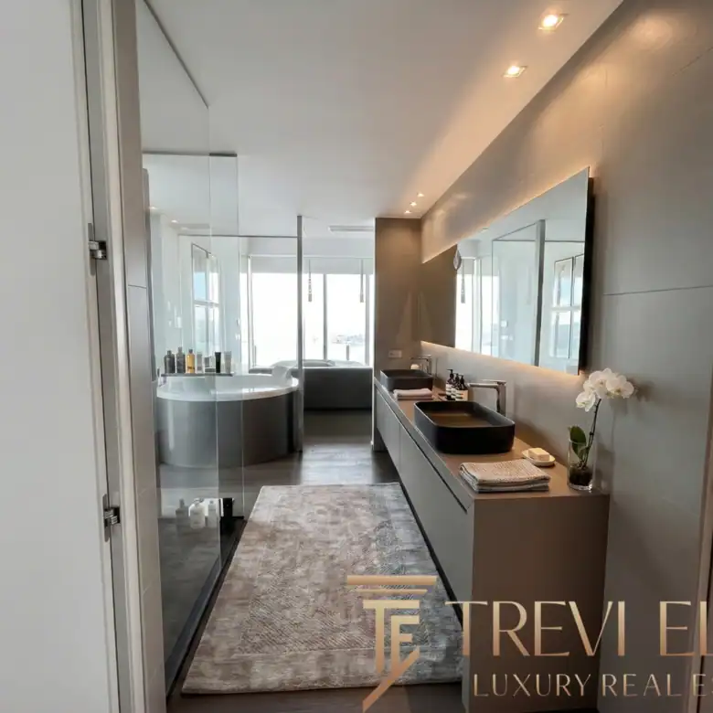 Modern bathroom with a walk-in glass shower and dual-tone tiling.