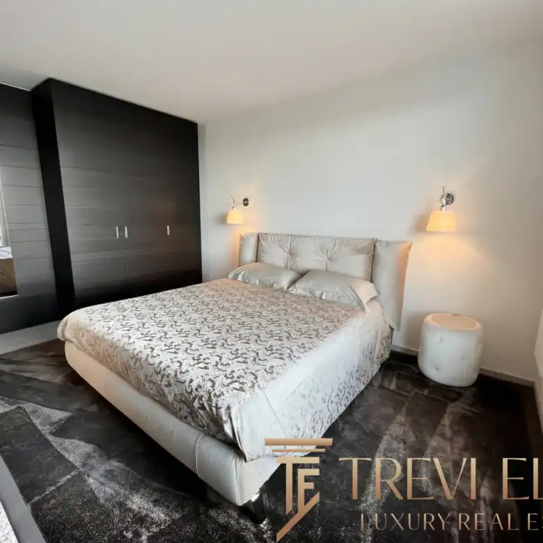 Modern bedroom with dark wood accents and plush grey bedding.
