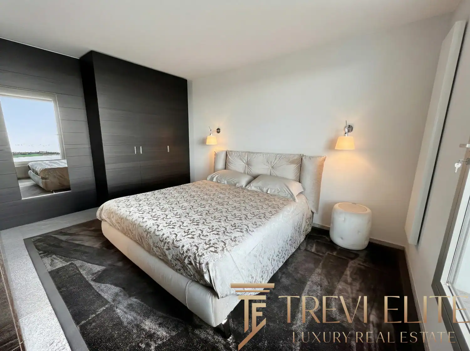 Modern bedroom with dark wood accents and plush grey bedding.