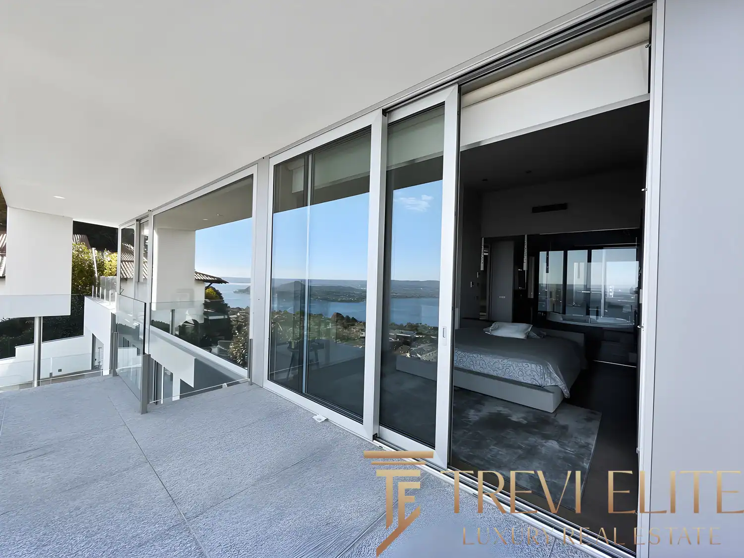 Wide terrace view with glass railings and a clear vista of the Italian lake district.
