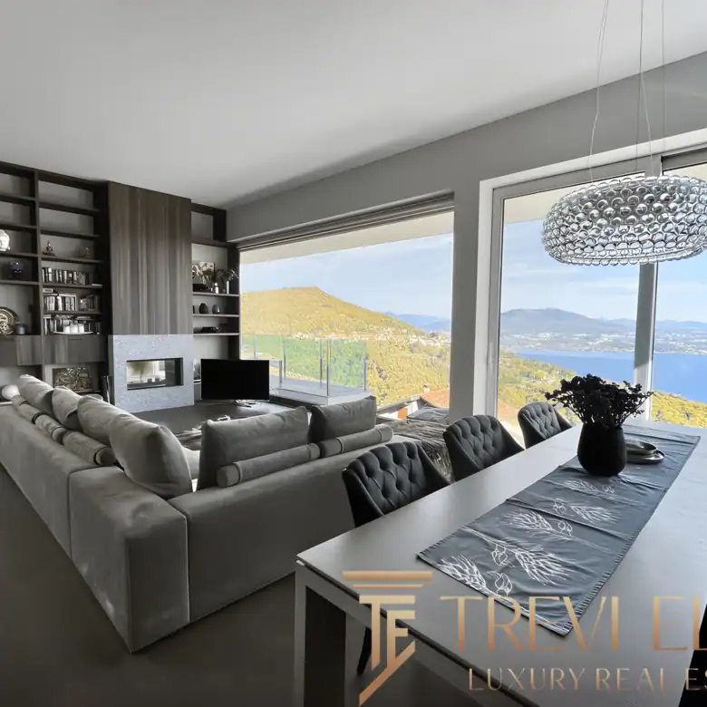 Dining table set for six with a modern chandelier and lake panorama.