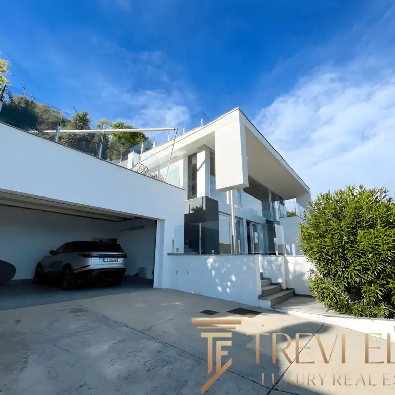 Exterior entrance showing the garage and the villa’s clean, white concrete lines.
