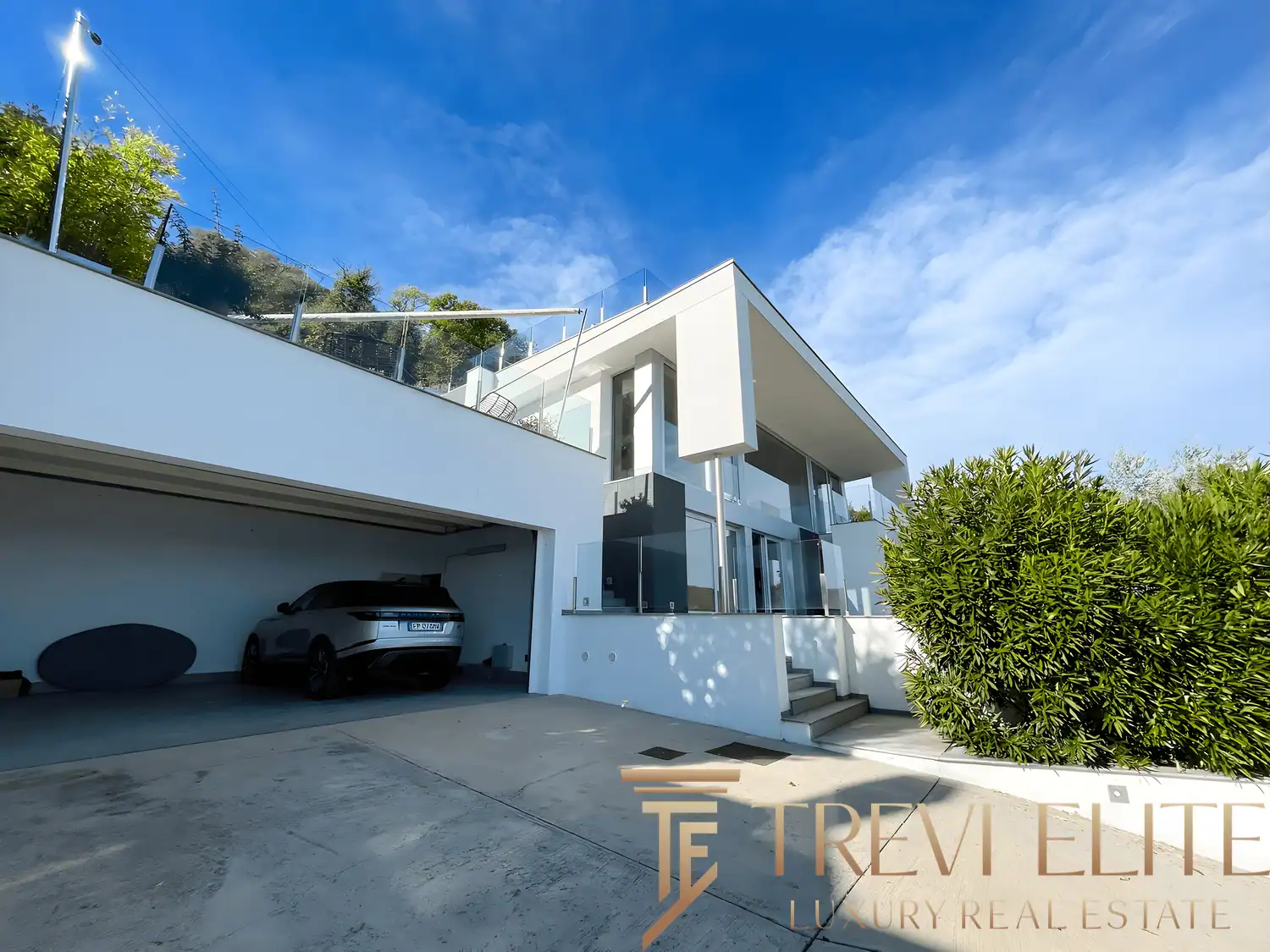 Exterior entrance showing the garage and the villa’s clean, white concrete lines.